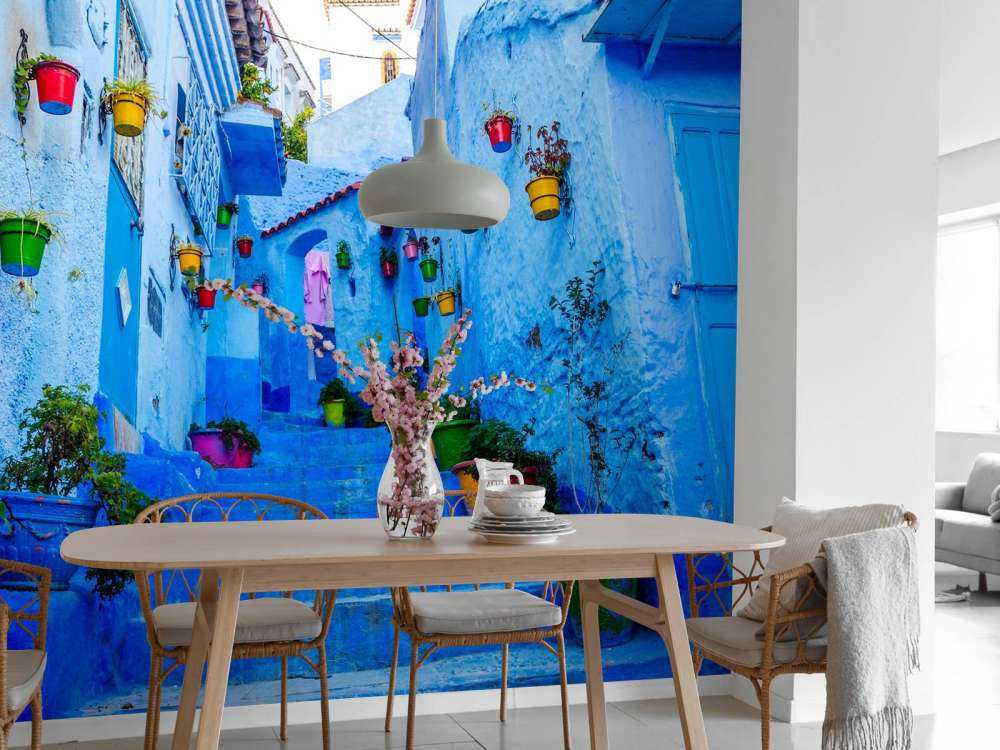 Blauwe straat met kleurrijke bloemenemmers in Marokko