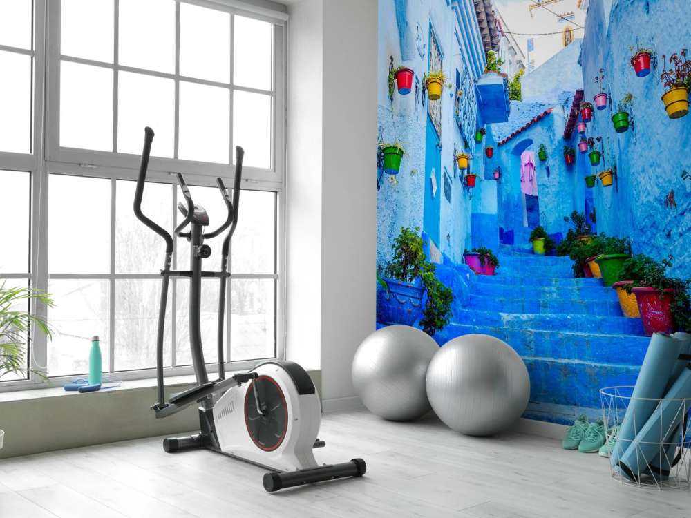 Blauwe straat met kleurrijke bloemenemmers in Marokko