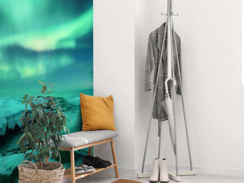 Green northern lights above snowy rocks